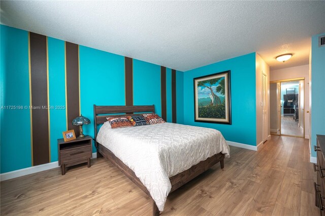 bedroom with light hardwood / wood-style floors, a closet, and a textured ceiling