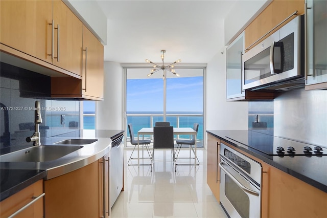 kitchen with a chandelier, a water view, appliances with stainless steel finishes, light tile patterned flooring, and sink