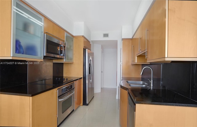 kitchen with appliances with stainless steel finishes, light tile patterned floors, tasteful backsplash, and sink