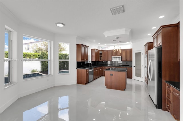 kitchen with stainless steel appliances, a kitchen island, decorative backsplash, and ornamental molding