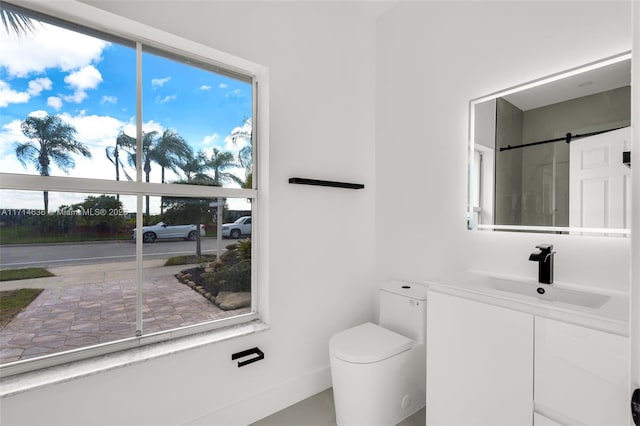 bathroom with toilet, vanity, and a healthy amount of sunlight