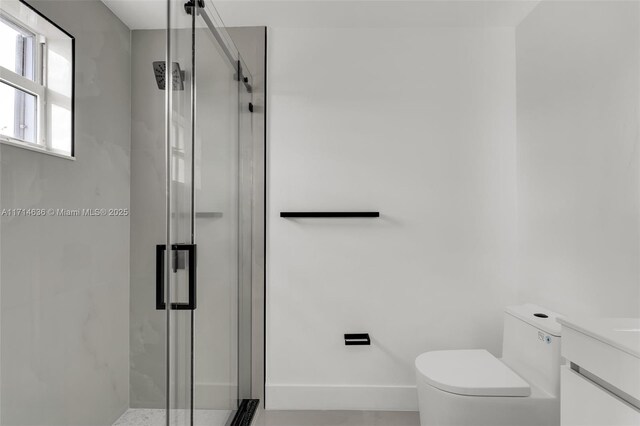 bathroom featuring vanity, a shower with shower door, and toilet