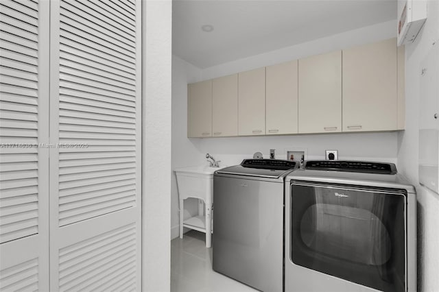 laundry area with cabinets, washing machine and clothes dryer, and light tile patterned floors