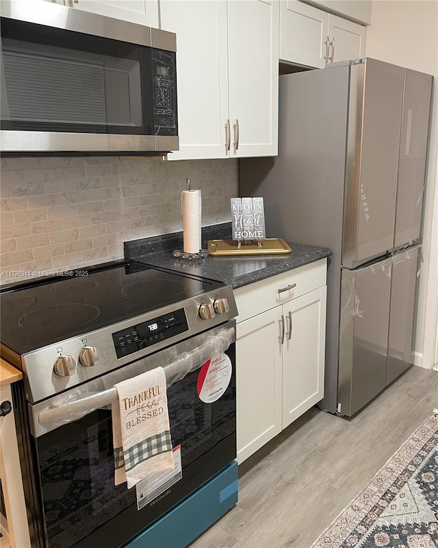 kitchen featuring white cabinets, decorative backsplash, light hardwood / wood-style flooring, and appliances with stainless steel finishes