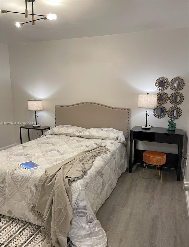 bedroom featuring an inviting chandelier and hardwood / wood-style floors