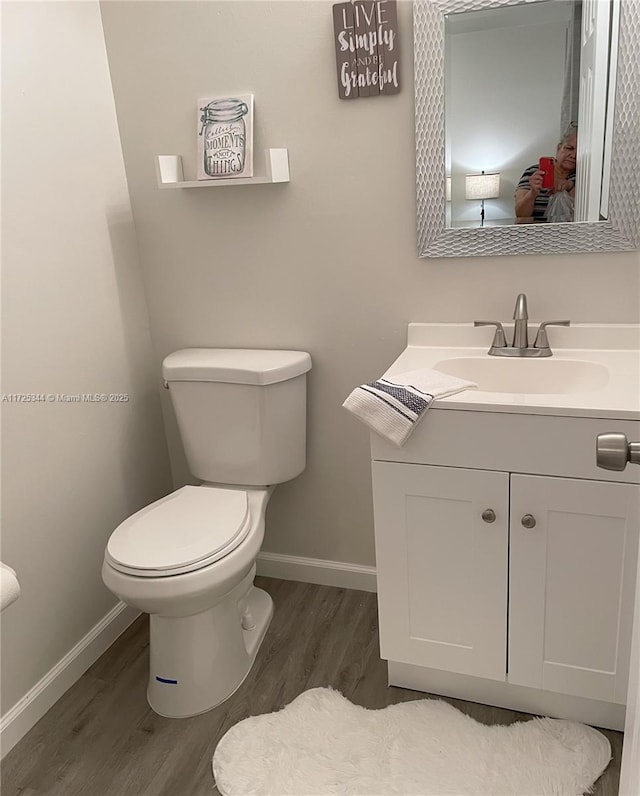 bathroom with toilet, wood-type flooring, and vanity