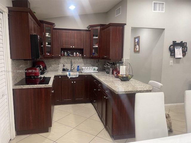 kitchen with light stone countertops, light tile patterned floors, tasteful backsplash, black electric stovetop, and sink