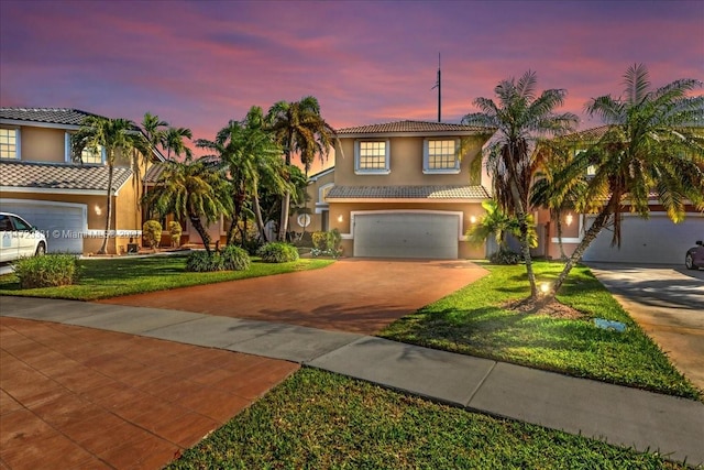 mediterranean / spanish-style home featuring a garage and a yard