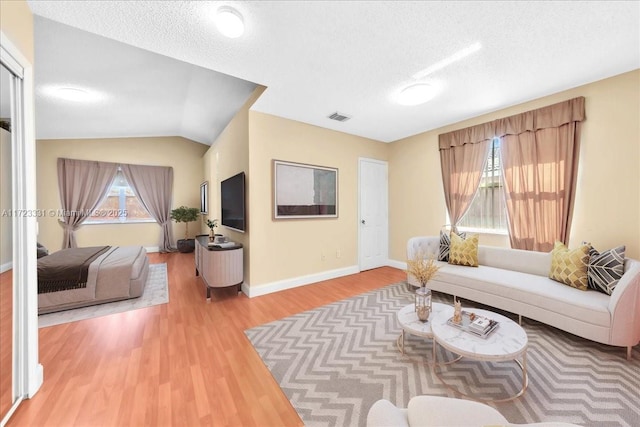 living room featuring lofted ceiling, a textured ceiling, a wealth of natural light, and hardwood / wood-style flooring