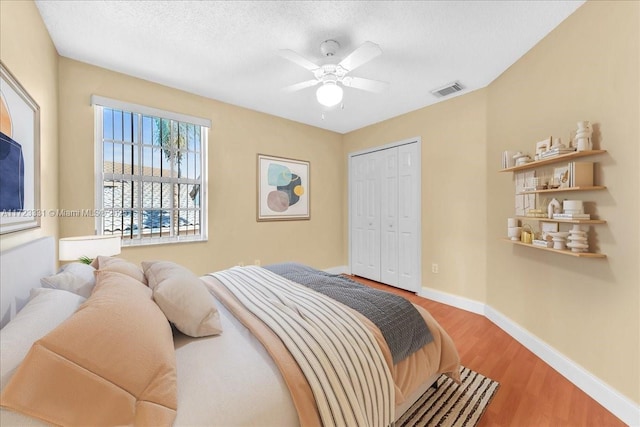 bedroom with hardwood / wood-style floors, a closet, ceiling fan, and a textured ceiling