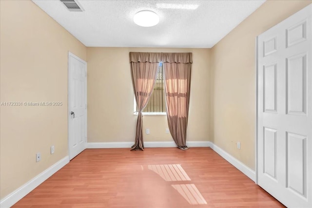 empty room featuring hardwood / wood-style flooring and a textured ceiling