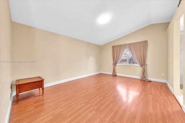 spare room featuring lofted ceiling and hardwood / wood-style floors