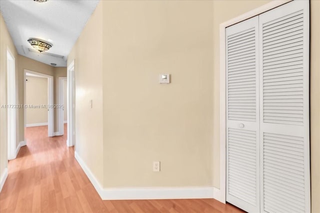 hallway with a textured ceiling and light hardwood / wood-style floors