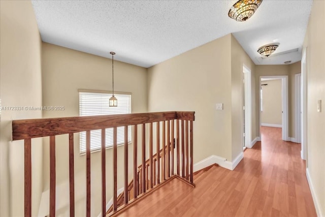 hallway with light hardwood / wood-style floors and a textured ceiling