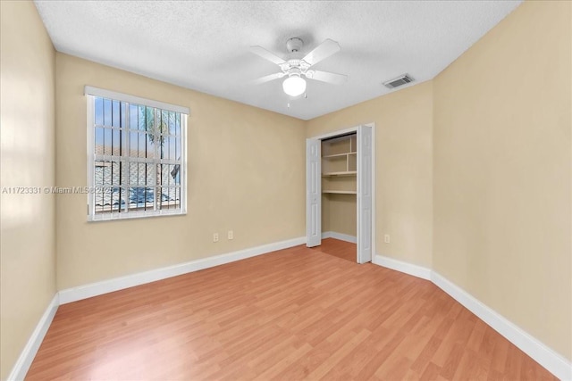 unfurnished bedroom with wood-type flooring, a closet, ceiling fan, and a textured ceiling