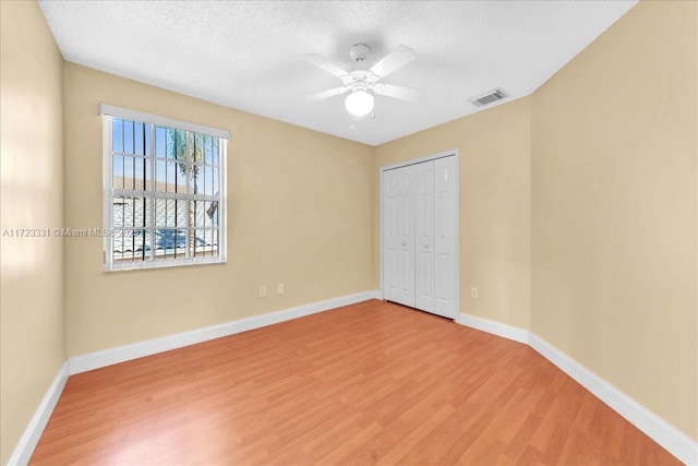 unfurnished bedroom with hardwood / wood-style floors, a closet, ceiling fan, and a textured ceiling