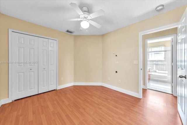 unfurnished bedroom featuring ceiling fan, light wood-type flooring, a closet, and a textured ceiling