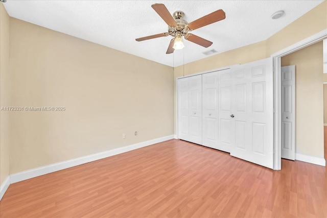 unfurnished bedroom featuring ceiling fan, a closet, a textured ceiling, and wood-type flooring