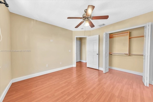 unfurnished bedroom featuring ceiling fan, a closet, a textured ceiling, and hardwood / wood-style flooring