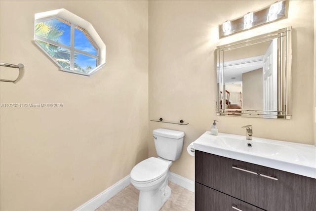 bathroom with toilet, vanity, and tile patterned floors