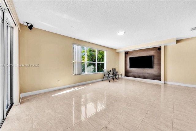 unfurnished living room with a textured ceiling and light tile patterned flooring