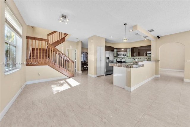 kitchen with kitchen peninsula, stainless steel appliances, tasteful backsplash, and dark brown cabinetry