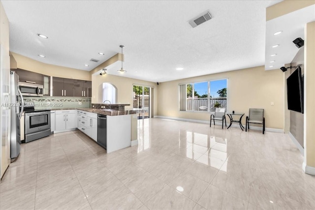 kitchen featuring appliances with stainless steel finishes, kitchen peninsula, ceiling fan, sink, and backsplash