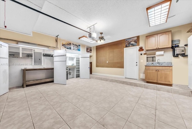 interior space with a garage door opener, ceiling fan, white refrigerator, electric panel, and sink