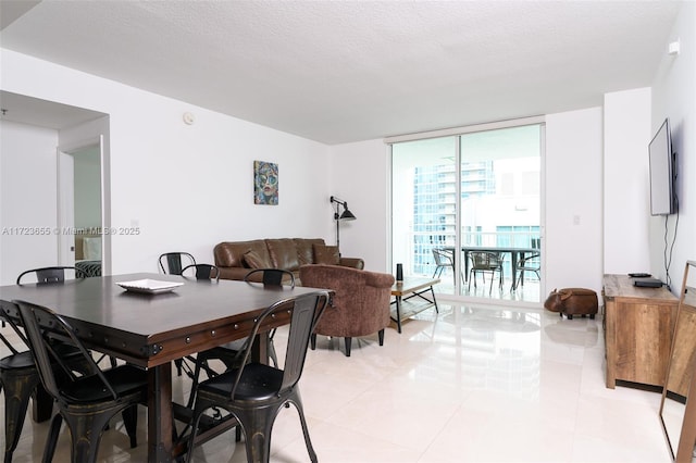 dining space featuring a textured ceiling, a wall of windows, and light tile patterned floors