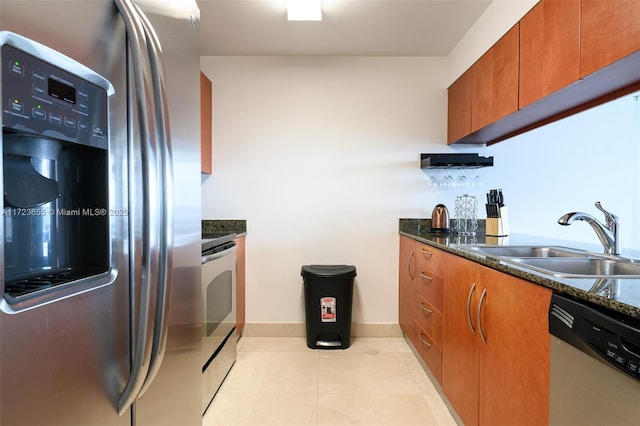 kitchen featuring appliances with stainless steel finishes, dark stone countertops, light tile patterned floors, and sink