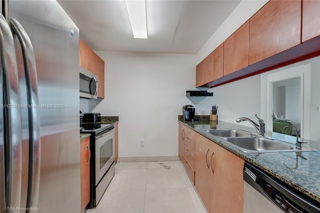 kitchen featuring stainless steel appliances, dark stone countertops, light tile patterned flooring, and sink