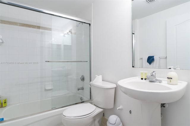 bathroom featuring bath / shower combo with glass door and toilet