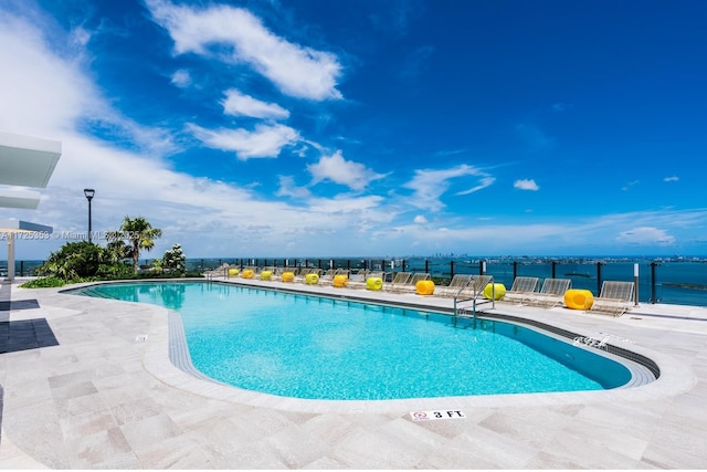 view of swimming pool featuring a water view and a patio area