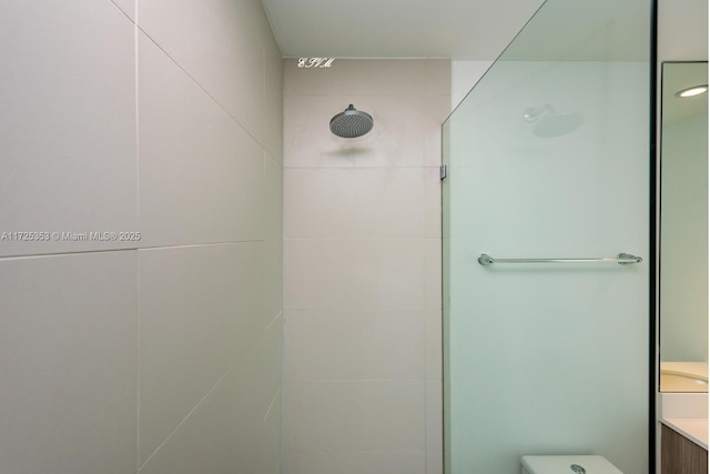 bathroom with tiled shower and vanity