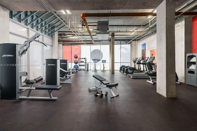 gym with floor to ceiling windows and a high ceiling