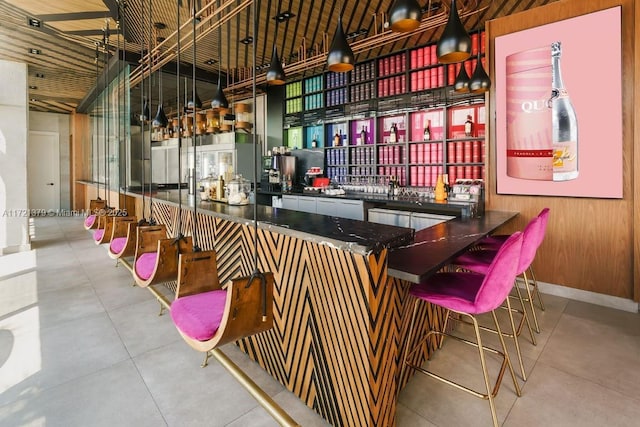 bar with wood ceiling, hanging light fixtures, wood walls, and a high ceiling