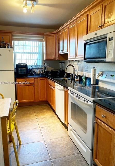 kitchen with sink, white appliances, and light tile patterned floors