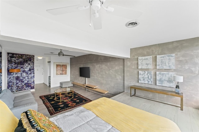 living room featuring tile walls, hardwood / wood-style flooring, and ceiling fan