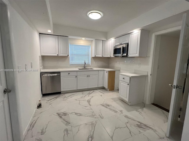 kitchen featuring sink, stainless steel appliances, white cabinetry, and backsplash