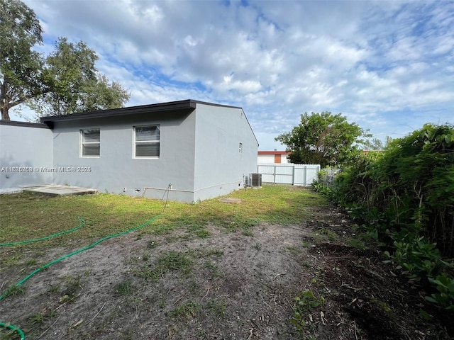 view of side of home with a yard and central AC unit