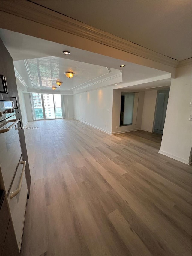 unfurnished living room with light wood-type flooring and ornamental molding