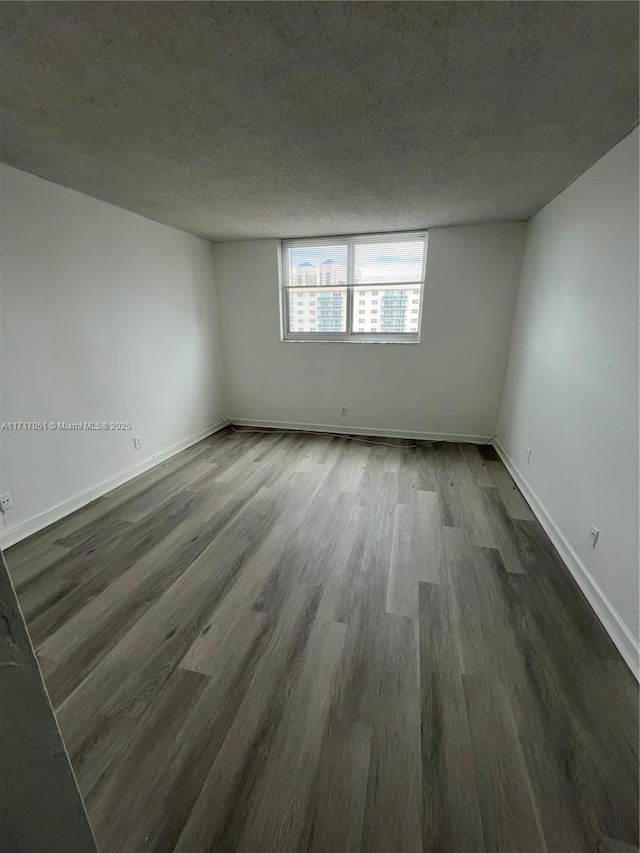 spare room featuring dark wood-type flooring and a textured ceiling