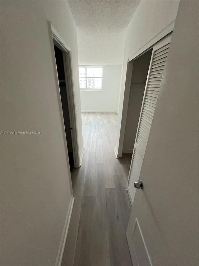 hall with wood-type flooring and a textured ceiling