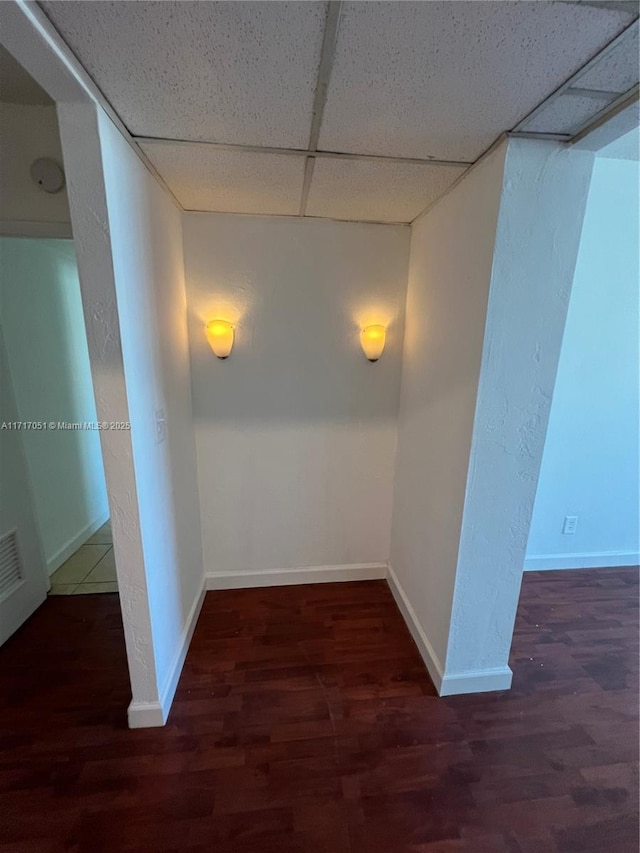 hallway with a drop ceiling and dark hardwood / wood-style floors