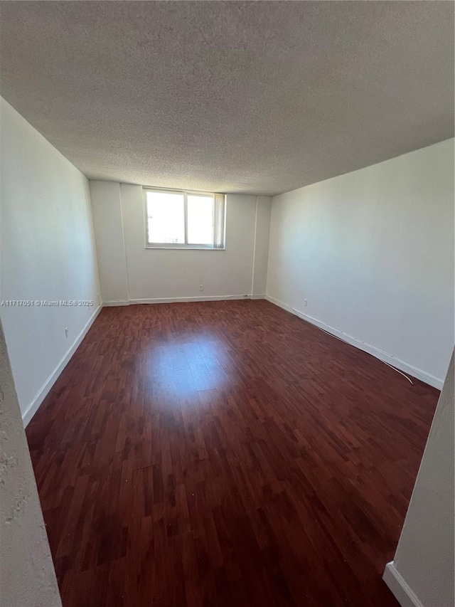 spare room featuring a textured ceiling and dark wood-type flooring