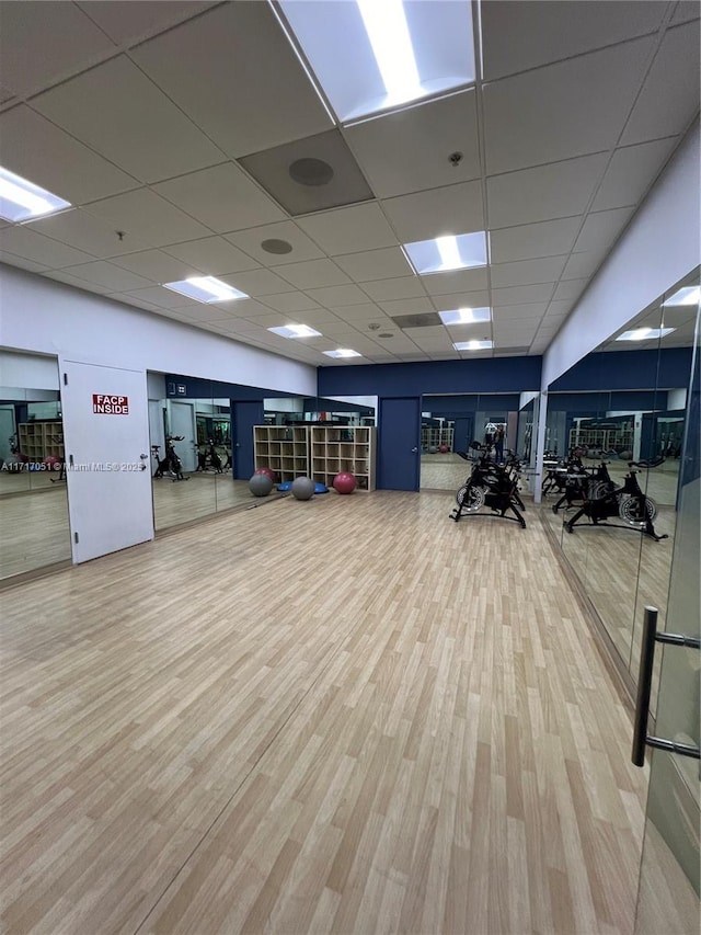 workout area featuring a drop ceiling and wood-type flooring