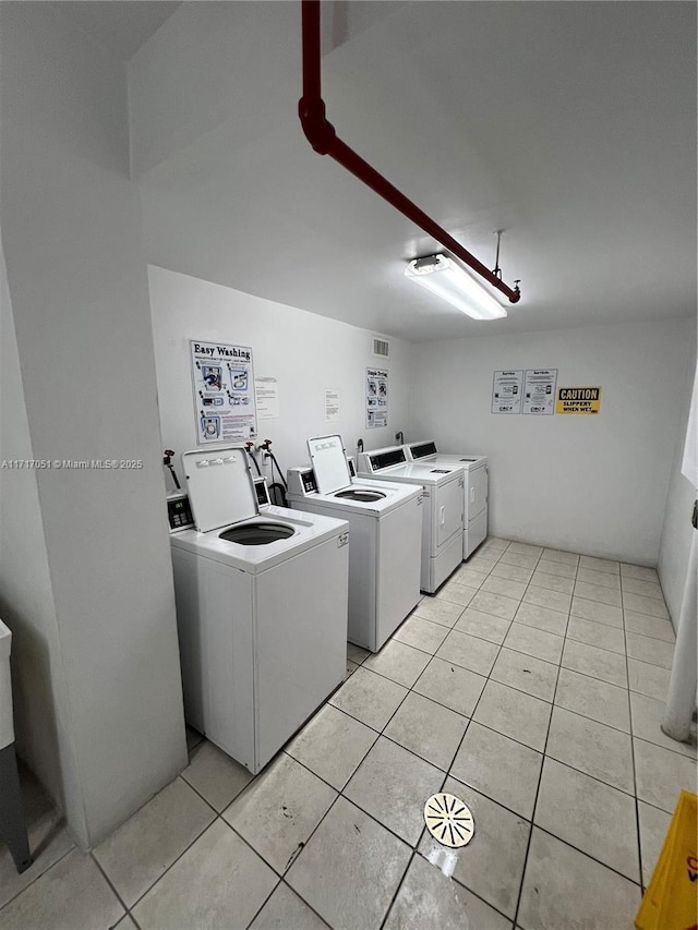 clothes washing area with separate washer and dryer and light tile patterned floors