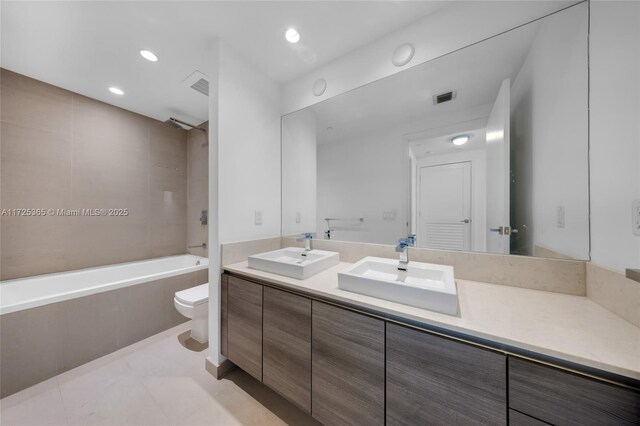 full bathroom featuring vanity, toilet, tiled shower / bath combo, and tile patterned flooring