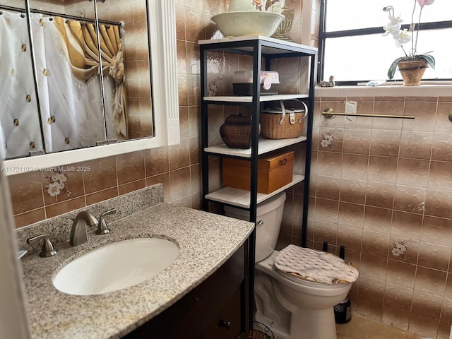 bathroom with toilet, tile walls, and vanity