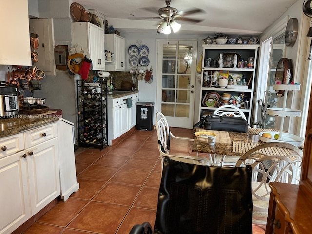 kitchen featuring ceiling fan, tasteful backsplash, dark stone countertops, white cabinetry, and dark tile patterned floors